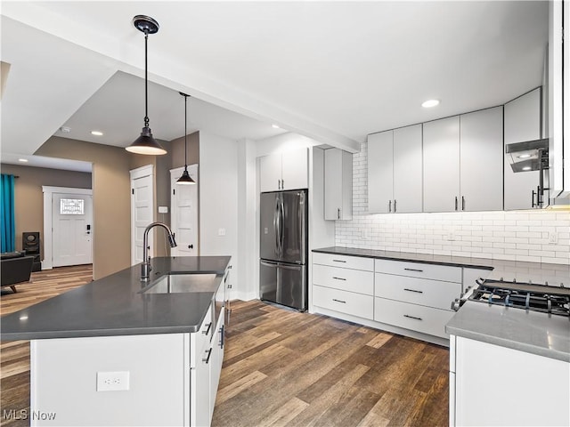 kitchen with sink, backsplash, stainless steel fridge, decorative light fixtures, and a kitchen island