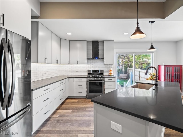 kitchen with sink, wall chimney exhaust hood, tasteful backsplash, decorative light fixtures, and appliances with stainless steel finishes