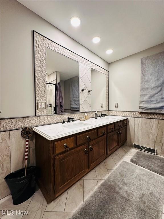 bathroom with vanity and tile walls