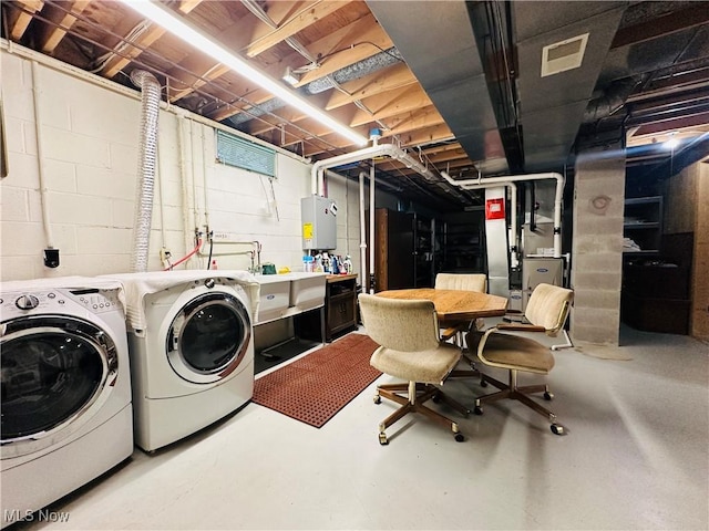 washroom with water heater, sink, and washing machine and clothes dryer