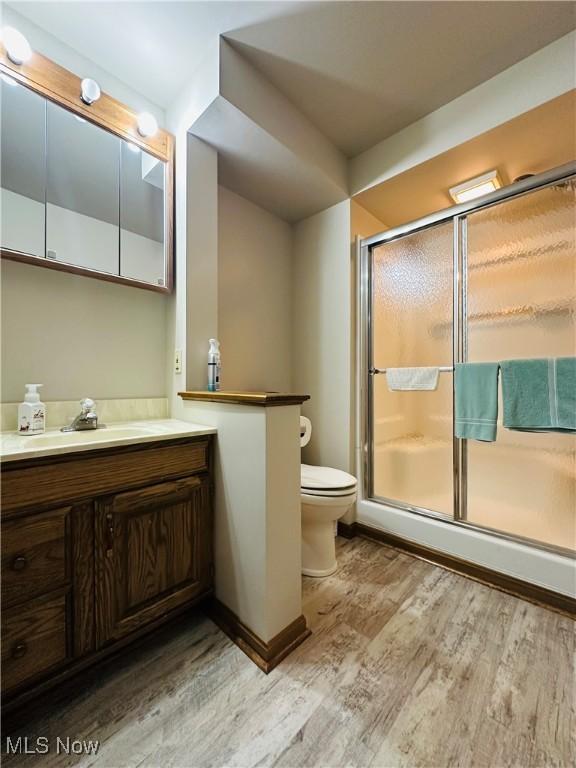 bathroom with vanity, wood-type flooring, a shower with shower door, and toilet