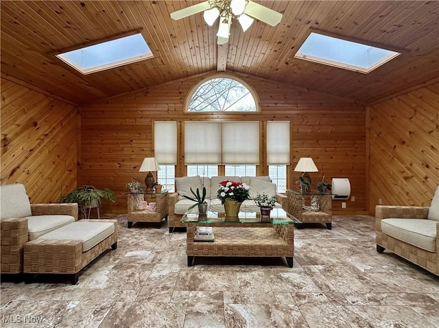 living area with wooden walls, lofted ceiling with skylight, ceiling fan, and wooden ceiling