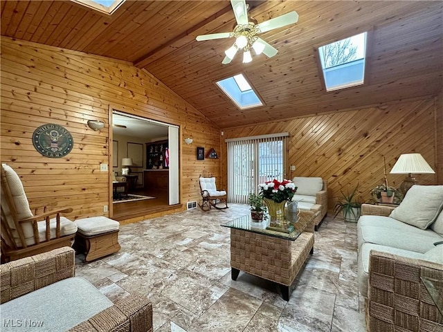 living room with vaulted ceiling with skylight, ceiling fan, wood walls, and wood ceiling