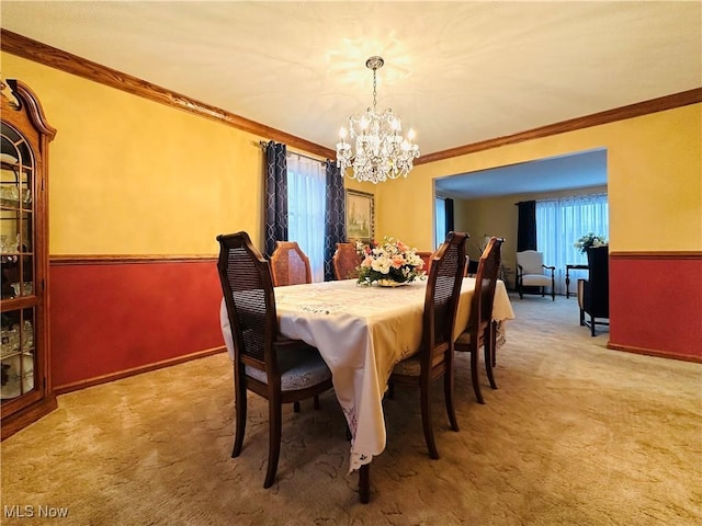 carpeted dining space featuring ornamental molding and an inviting chandelier