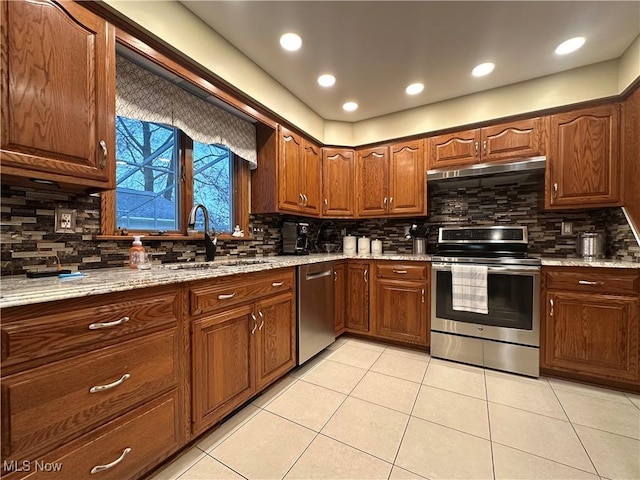 kitchen featuring sink, decorative backsplash, light tile patterned floors, light stone counters, and stainless steel appliances