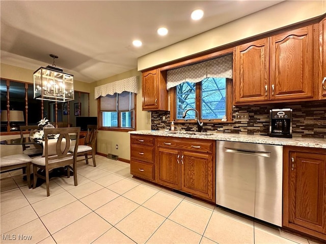 kitchen with light stone countertops, tasteful backsplash, sink, dishwasher, and a chandelier