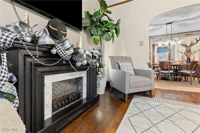 living room featuring a fireplace, dark hardwood / wood-style flooring, a chandelier, and crown molding