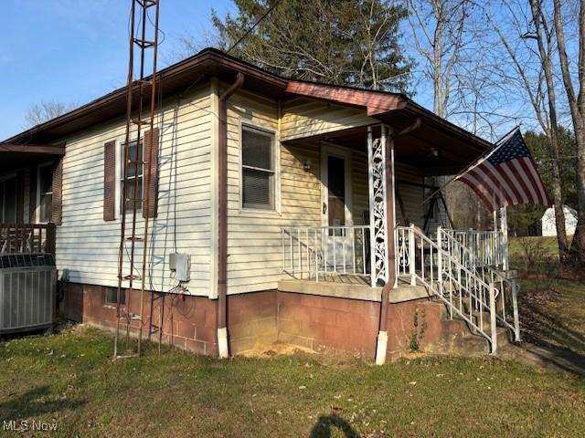 view of side of home with central AC, a yard, and covered porch