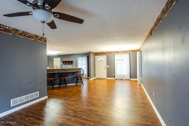 unfurnished living room with hardwood / wood-style floors, ceiling fan, and a textured ceiling