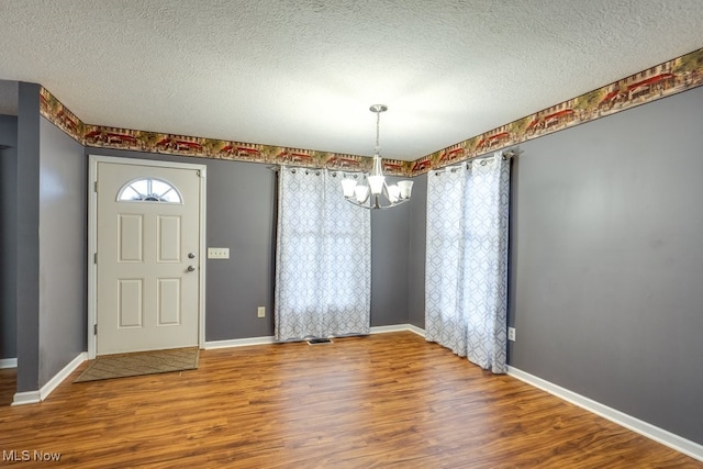 foyer with hardwood / wood-style flooring, a notable chandelier, and a textured ceiling