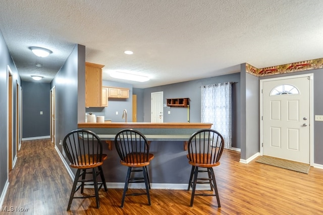 kitchen featuring hardwood / wood-style floors, light brown cabinetry, a breakfast bar area, and sink