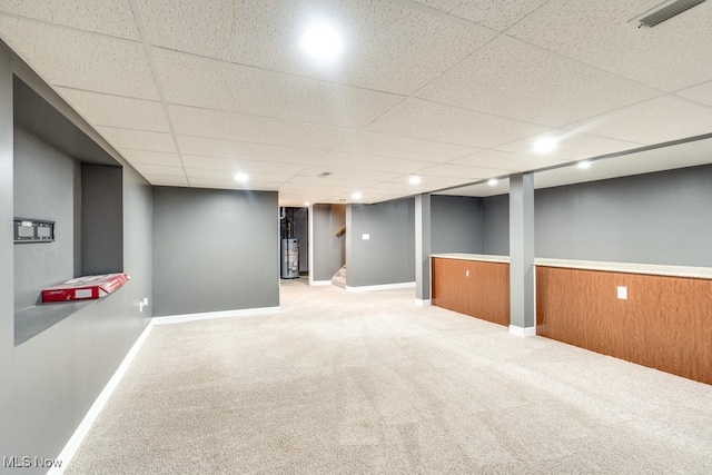 basement with carpet, a paneled ceiling, and water heater