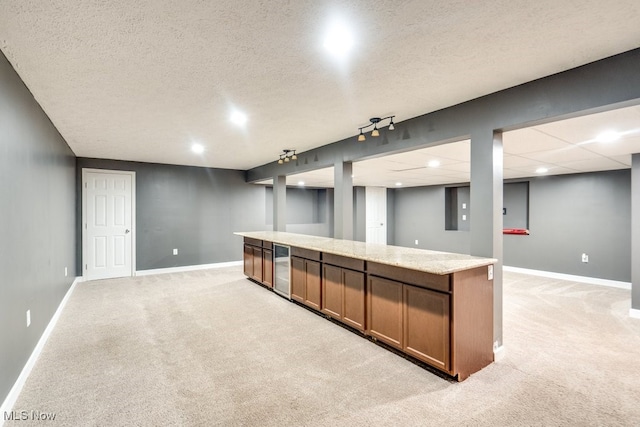 interior space with light carpet, rail lighting, light stone countertops, and a textured ceiling