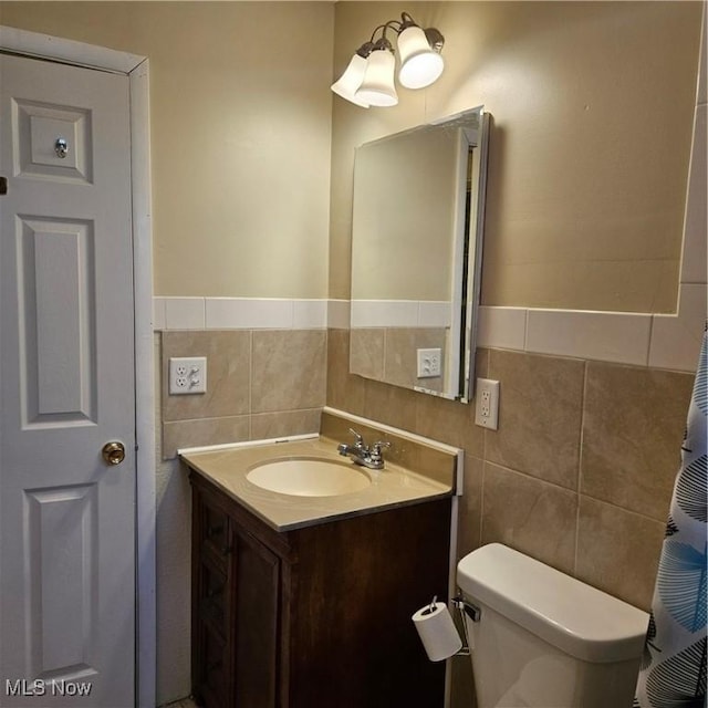 bathroom featuring vanity, tile walls, and toilet