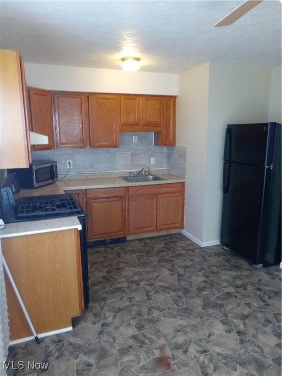 kitchen with black refrigerator, sink, and backsplash