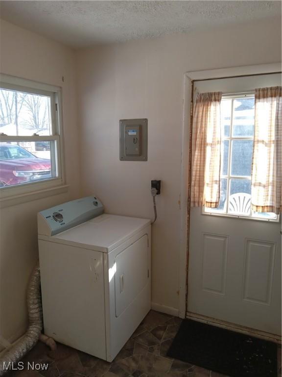 laundry room featuring washer / dryer, electric panel, and a textured ceiling