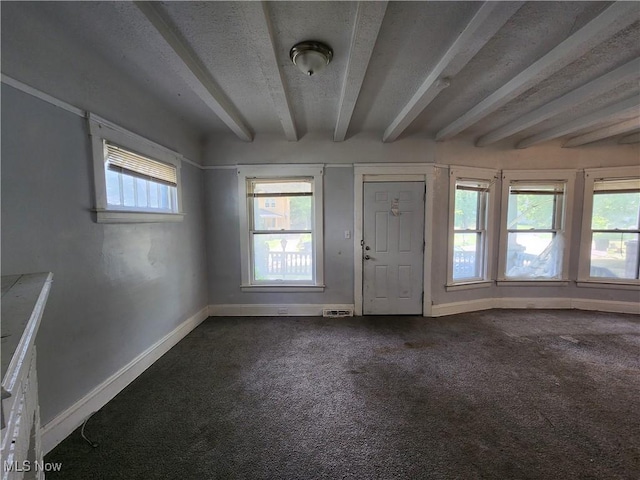 foyer featuring dark carpet and a textured ceiling