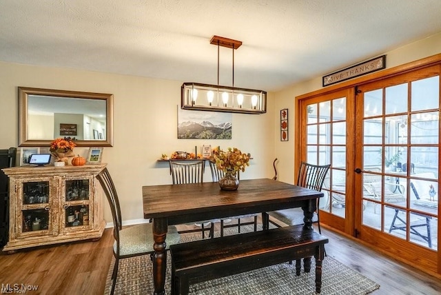 dining space with french doors, wood-type flooring, and a textured ceiling