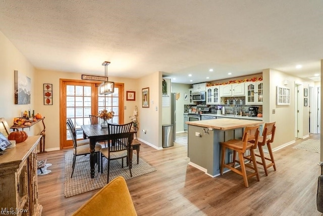 kitchen with white cabinets, appliances with stainless steel finishes, and light hardwood / wood-style flooring