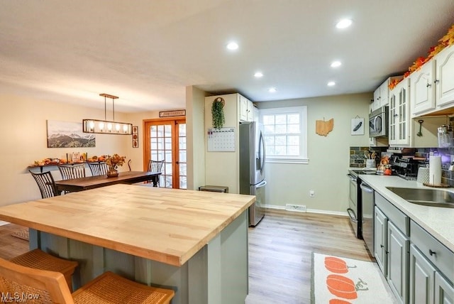 kitchen with white cabinets, pendant lighting, stainless steel appliances, and gray cabinets