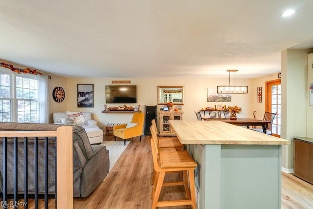 kitchen featuring a breakfast bar, light hardwood / wood-style floors, hanging light fixtures, and a chandelier