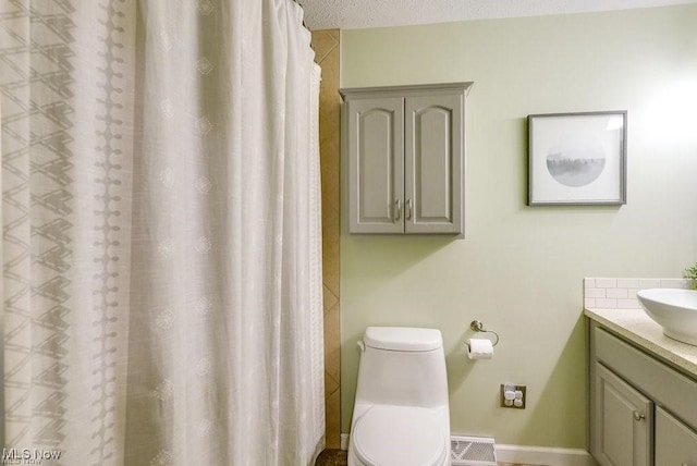 bathroom with a textured ceiling, vanity, and toilet