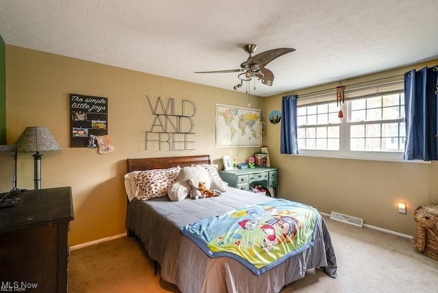 carpeted bedroom featuring ceiling fan and a textured ceiling