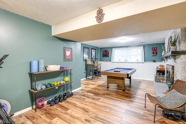 rec room with hardwood / wood-style flooring, a fireplace, a textured ceiling, and billiards