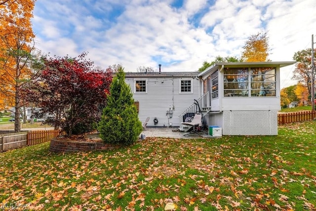 back of house with a lawn, a patio area, and a sunroom