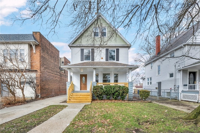 traditional style home featuring a porch, fence, and a front lawn