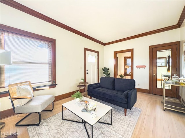 living area with ornamental molding, light wood-type flooring, and baseboards