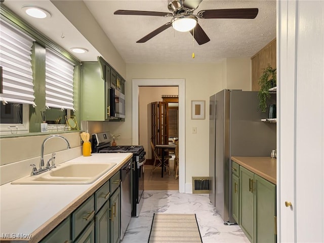 kitchen featuring ceiling fan, sink, stainless steel appliances, a textured ceiling, and green cabinetry