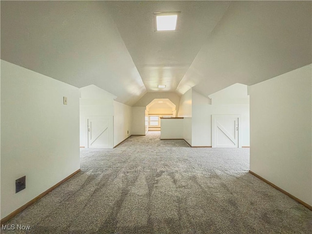 additional living space with carpet flooring and vaulted ceiling