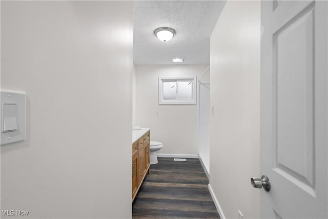 bathroom with hardwood / wood-style floors, vanity, a textured ceiling, and toilet