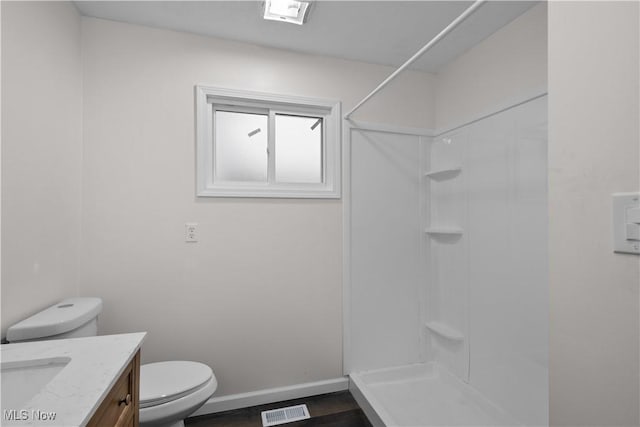 bathroom with hardwood / wood-style flooring, toilet, vanity, and walk in shower