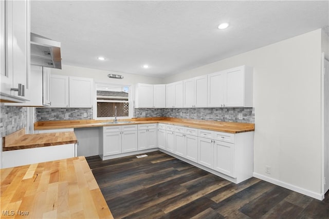 kitchen with butcher block counters, sink, dark wood-type flooring, tasteful backsplash, and white cabinets