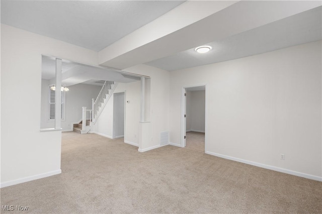 basement with light carpet and a chandelier