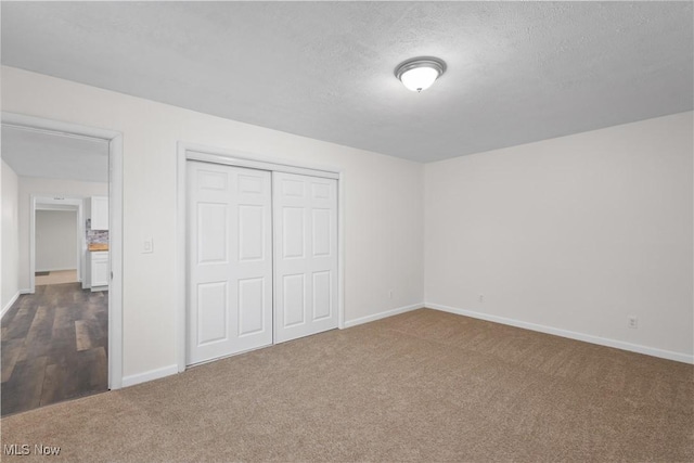 unfurnished bedroom featuring a textured ceiling, carpet floors, and a closet