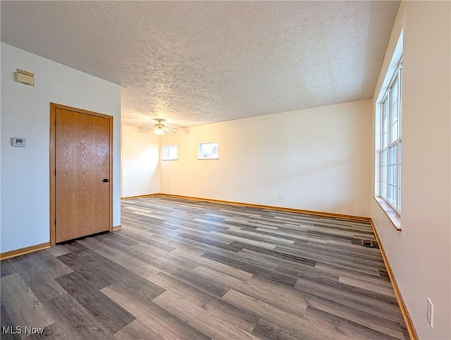 empty room featuring ceiling fan, a textured ceiling, and dark wood-type flooring