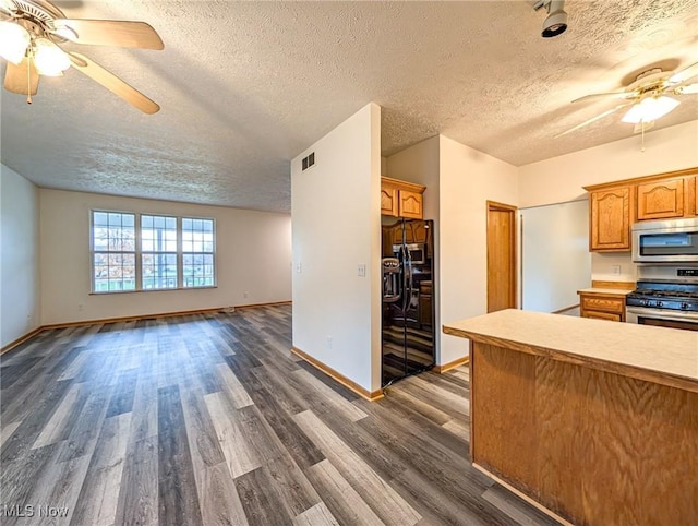 kitchen with a textured ceiling, ceiling fan, dark wood-type flooring, and appliances with stainless steel finishes