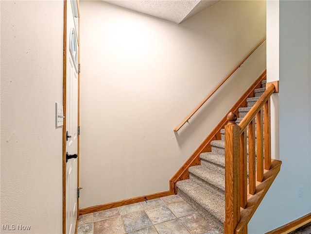 stairway featuring a textured ceiling