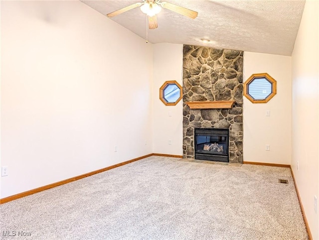 unfurnished living room featuring carpet flooring, ceiling fan, lofted ceiling, a textured ceiling, and a fireplace