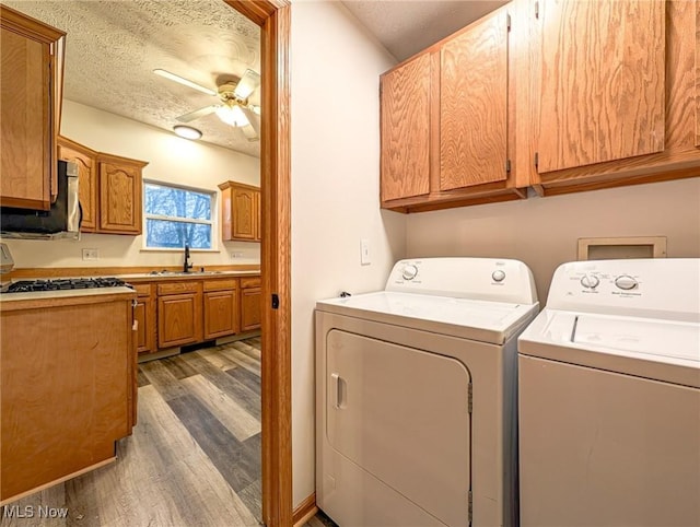 clothes washing area with sink, ceiling fan, washing machine and dryer, a textured ceiling, and dark hardwood / wood-style flooring