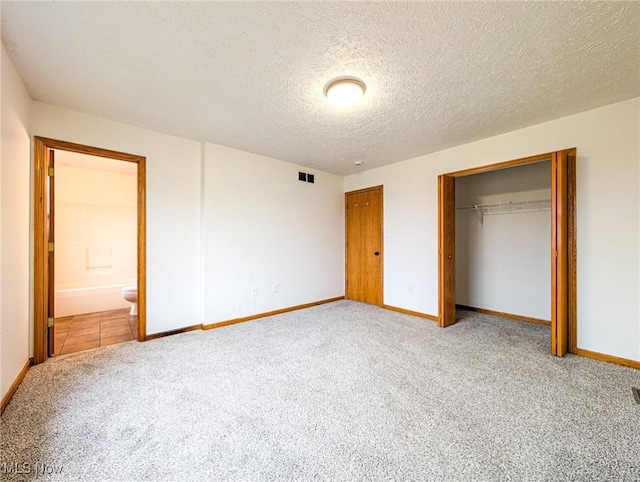 unfurnished bedroom with carpet floors, a textured ceiling, connected bathroom, and a closet