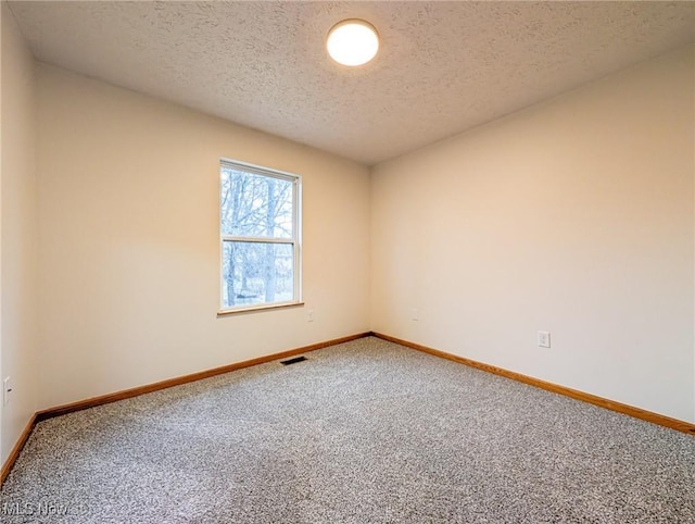 carpeted empty room with a textured ceiling