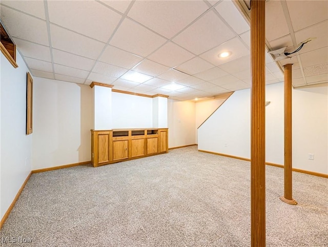 basement with a paneled ceiling and light colored carpet