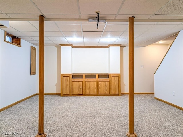 basement with a paneled ceiling and light carpet