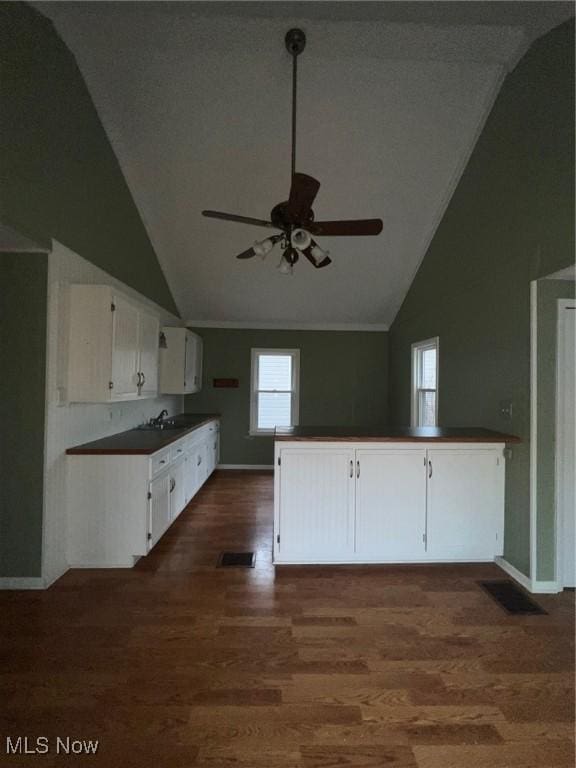 kitchen featuring kitchen peninsula, dark hardwood / wood-style flooring, ceiling fan, high vaulted ceiling, and white cabinetry