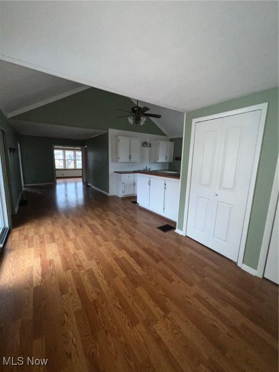 unfurnished living room featuring ceiling fan, lofted ceiling, and dark wood-type flooring