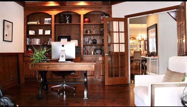 home office featuring french doors, wooden walls, built in features, and a notable chandelier